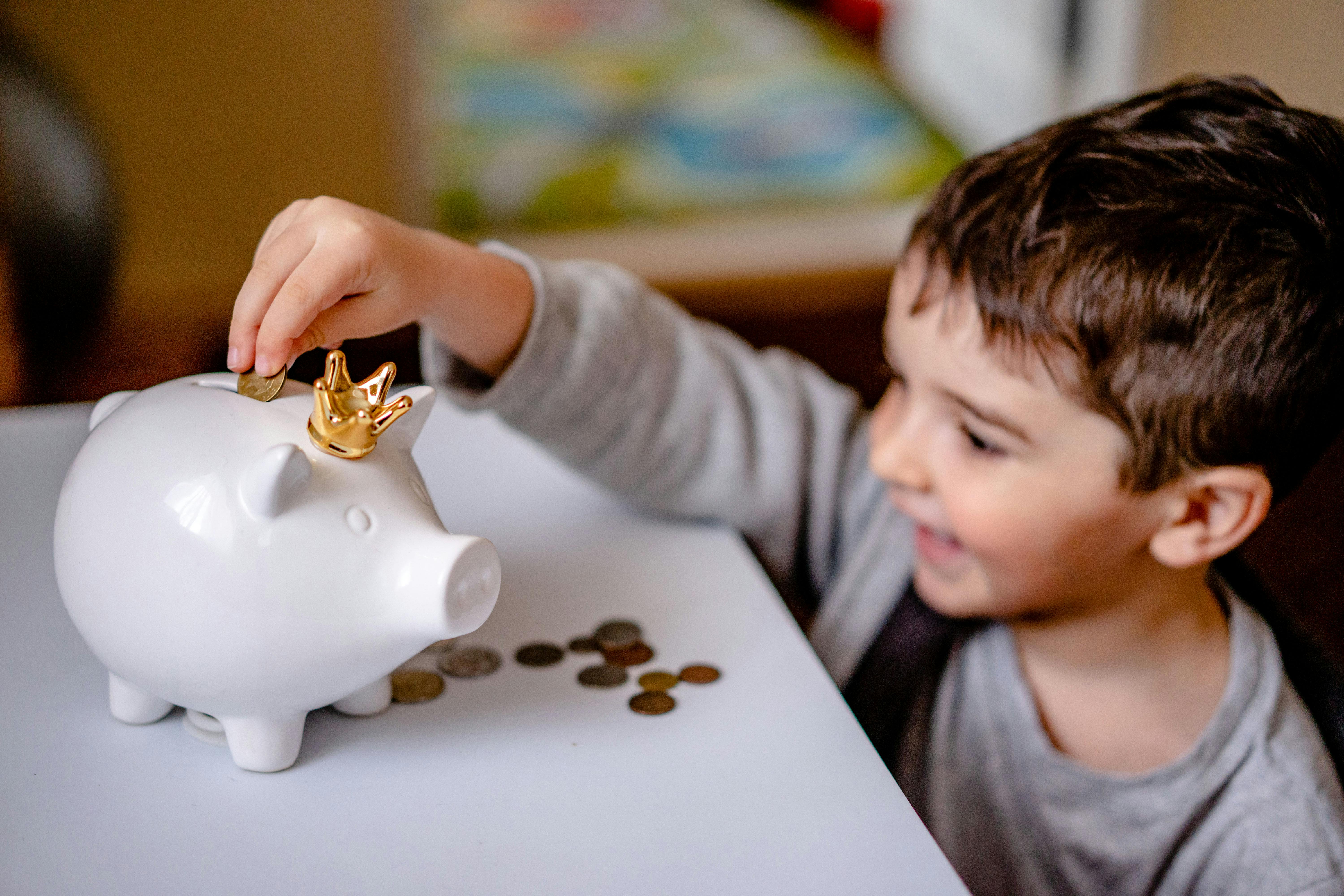 Child putting coin in piggy bank with golden crown